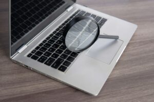Closeup image of magnifying glass and laptop.