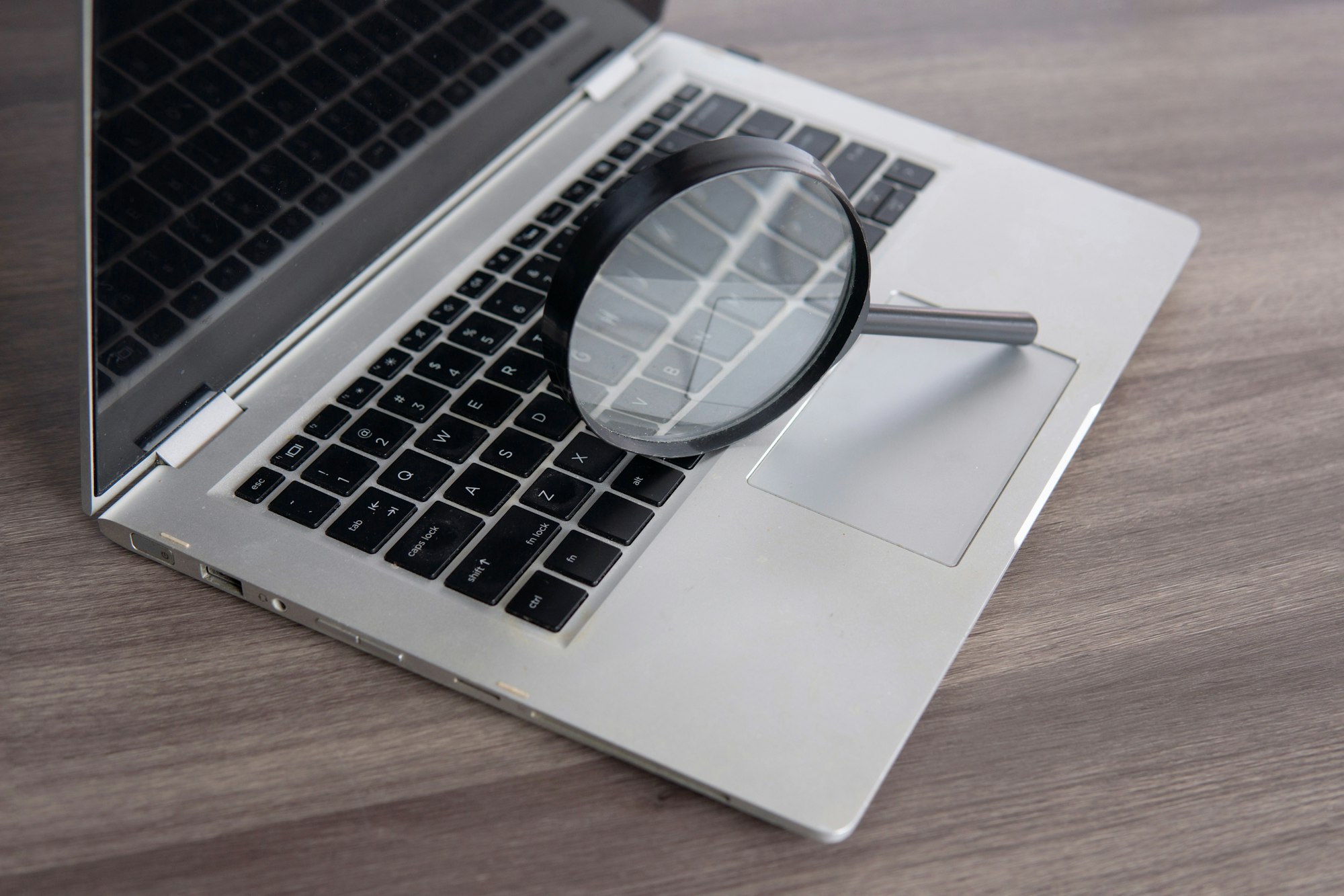 Closeup image of magnifying glass and laptop.